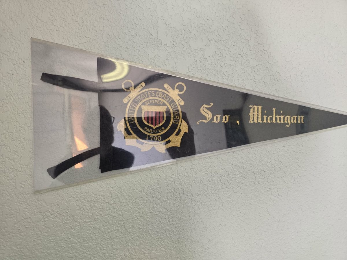 A vintage United States Coast Guard pennant reading Soo, Michigan, on the shop wall