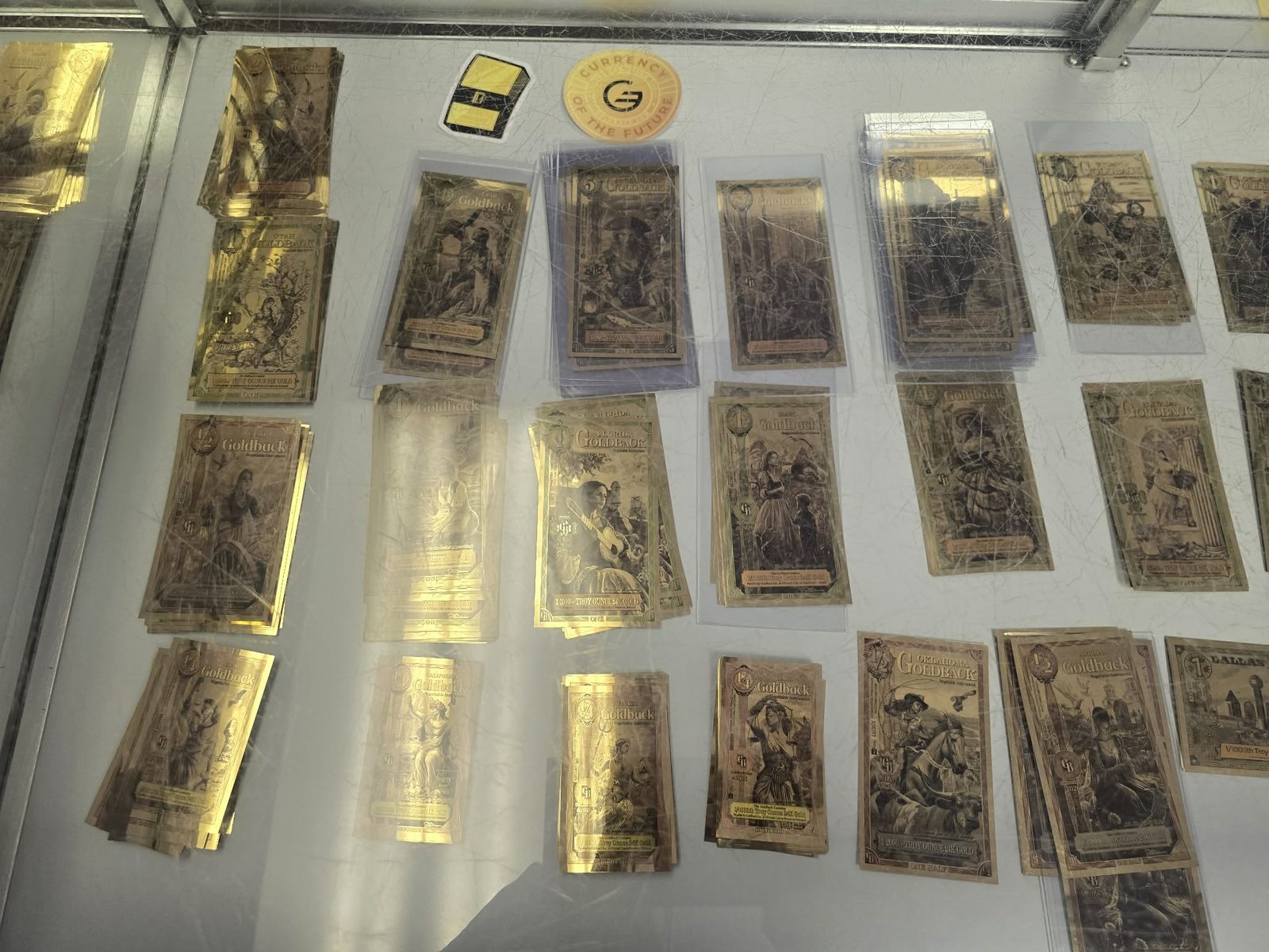 Goldback notes from several states laid out in a display case