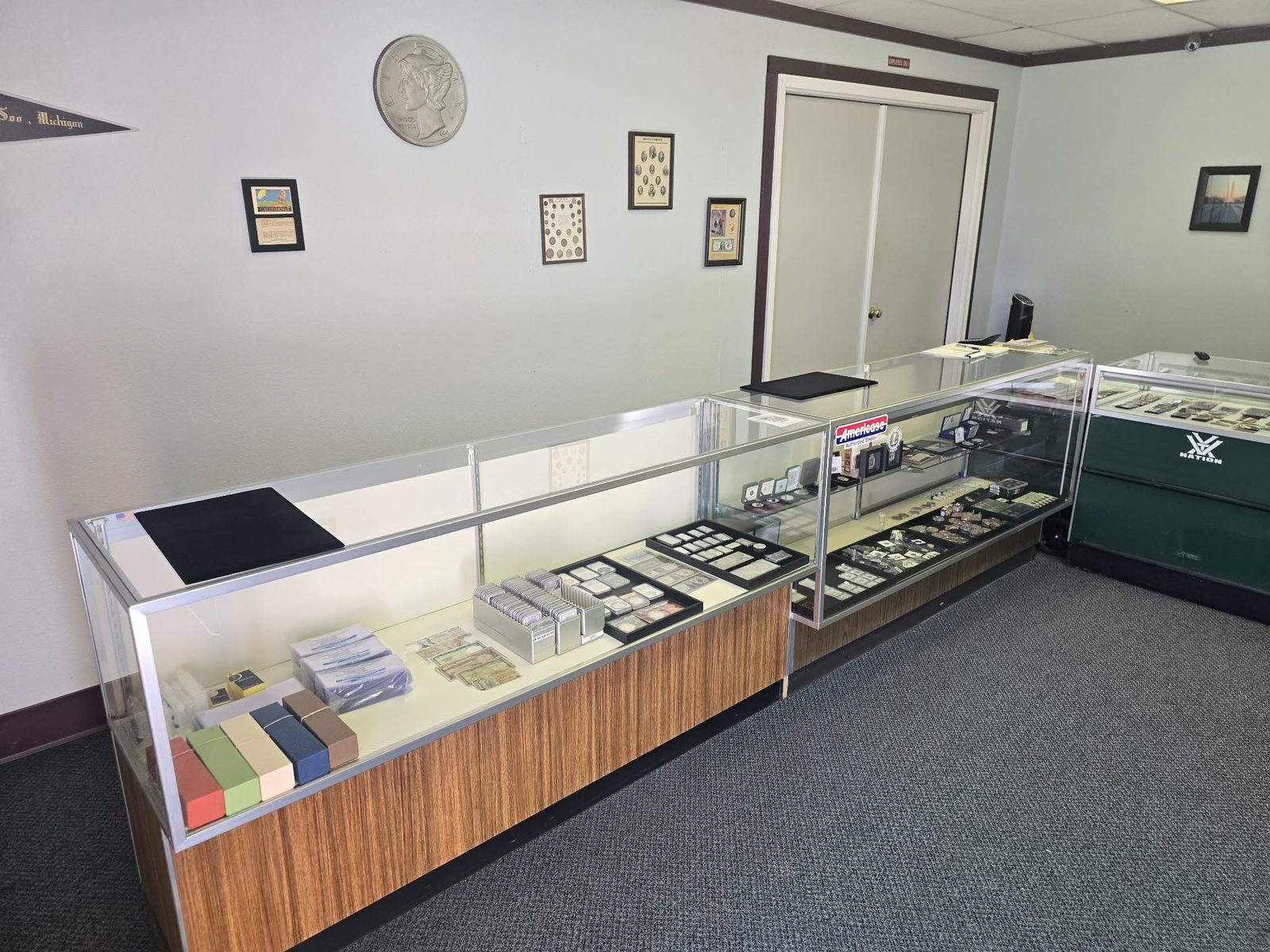 Inside the shop: display cases along two walls, a Mercury dime on the wall and a Coast Guard pennant