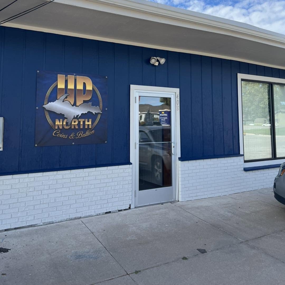 The UP North Coins & Bullion storefront at 408 Magazine St, Sault Ste. Marie — blue siding, white brick, and the sign over the door